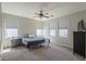 Bright bedroom featuring a ceiling fan, carpet floors, a large bed, and natural light from multiple windows at 18811 E Pelican Ct, Queen Creek, AZ 85142