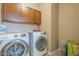 Functional laundry room with modern side by side washer and dryer and overhead storage at 18811 E Pelican Ct, Queen Creek, AZ 85142