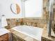 Relaxing soaking tub with tile surround next to a bright window with blind coverings and decor at 19403 E Arrowhead Trl, Queen Creek, AZ 85142