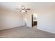 Bedroom boasts neutral walls, carpet, ceiling fan, and doorway to a bathroom at 22196 W Tonto St, Buckeye, AZ 85326
