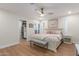 Bright main bedroom boasts a ceiling fan, wood floors, ensuite closet, and a stylish bench at the foot of the bed at 2402 E Cinnabar Ave, Phoenix, AZ 85028