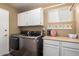 This functional laundry room features cabinetry, a folding counter, and modern washer and dryer at 2422 W Acoma Dr, Phoenix, AZ 85023