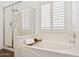 Elegant bathroom with a soaking tub, glass-enclosed shower, and plantation shutters at 28814 N 45Th St, Cave Creek, AZ 85331