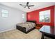 Cozy bedroom with a black bed frame, neutral carpet, and a bold red accent wall at 3247 E Creosote Ln, Gilbert, AZ 85298