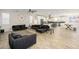 Open-concept living room with tile floors, ceiling fan, and comfortable dark sofas adjacent to a modern white kitchen at 3247 E Creosote Ln, Gilbert, AZ 85298