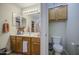 Bathroom featuring dual sinks, wood cabinets, and a separate toilet area at 43822 W Baker Dr, Maricopa, AZ 85138