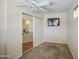 Neutral bedroom featuring wall-mounted TV, carpet floors, ceiling fan, and slider to the living room at 43822 W Baker Dr, Maricopa, AZ 85138