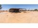 A large covered barn structure with hay bales and loose dirt in a rural, arid environment under clear sky at 49478 W Val Vista Rd, Maricopa, AZ 85139