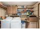 View of a laundry room with washer, dryer, wood cabinets and shelves at 49478 W Val Vista Rd, Maricopa, AZ 85139