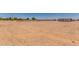 Large, flat dirt lot featuring rural fencing, various outbuildings, and sparse vegetation under a clear sky at 49478 W Val Vista Rd, Maricopa, AZ 85139