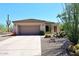 Tan single-story home featuring a two-car garage, desert landscaping, and a tile roof at 6966 E Bramble Berry Ln, Scottsdale, AZ 85266