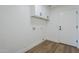 Clean, white laundry room with overhead storage cabinets, utility hookups and wood-look floors at 7144 E Lakeview Ave, Mesa, AZ 85209