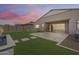 Backyard view includes patio area, turfed yard, water feature and sunset sky; an outdoor oasis at 7694 W Desert Spoon Dr, Peoria, AZ 85383