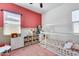 Colorful bedroom with pink accent wall, bed and white shelving unit, ideal for playful activities at 7694 W Desert Spoon Dr, Peoria, AZ 85383