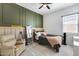 Cozy bedroom with olive green accent wall, lounge chair, plush blanket and neutral color carpet at 7694 W Desert Spoon Dr, Peoria, AZ 85383