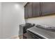 A modern laundry room features front load washer and dryer units and dark cabinetry for storage at 7694 W Desert Spoon Dr, Peoria, AZ 85383