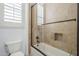 Tiled bathroom with glass door bathtub and shower combo with storage area and window at 10033 W Jj Ranch Rd, Peoria, AZ 85383