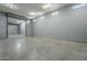 Garage interior featuring concrete flooring, overhead lighting, and a roll-up door at 10033 W Jj Ranch Rd, Peoria, AZ 85383