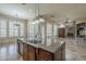 Kitchen island with a sink and granite countertops overlooking the living room with a fireplace at 10033 W Jj Ranch Rd, Peoria, AZ 85383