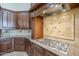 Kitchen featuring granite countertops, a cooktop, custom wood cabinets, and decorative backsplash tiles at 10033 W Jj Ranch Rd, Peoria, AZ 85383