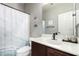 Clean bathroom featuring a single vanity, decorative mirror, and a shower with a stylish ocean-themed curtain at 11755 W Patrick Ln, Sun City, AZ 85373