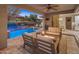 Covered patio and pool with travertine decking, a fire pit, seating, landscaping, and water features create a relaxing outdoor space at 13186 W Via Dona Rd, Peoria, AZ 85383