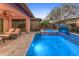 Backyard oasis features a pool with a raised spa, travertine decking, seating areas, and lush tropical landscaping at 13186 W Via Dona Rd, Peoria, AZ 85383