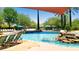 Luxurious community pool featuring a rock waterfall, lounge chairs, and shade structures on a sunny day at 13186 W Via Dona Rd, Peoria, AZ 85383