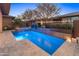 Inviting backyard pool and spa with travertine surround and water feature under a beautiful blue sky at 13186 W Via Dona Rd, Peoria, AZ 85383
