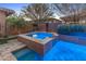 Raised spa is surrounded by lush landscaping, a waterfall feature, and travertine tile that provides a serene retreat at 13186 W Via Dona Rd, Peoria, AZ 85383