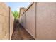 Narrow side yard featuring a gravel path between two stucco walls leading to a gate, providing access to the property at 14819 W Lupine Ln, Surprise, AZ 85374