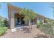 Serene backyard featuring a covered patio, desert landscaping, and lush green trees providing shade at 16417 W Piccadilly Rd, Goodyear, AZ 85395