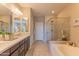 Bright bathroom featuring dual sinks, a soaking tub, and a glass-enclosed shower with tiled walls at 16417 W Piccadilly Rd, Goodyear, AZ 85395