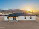 Aerial view of the home's rear exterior with a covered patio and mountain views at sunset at 16627 N Slate Ln, Maricopa, AZ 85139