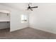 Bright bedroom with carpet and a ceiling fan, featuring a walk-in closet and views of the landscape at 16630 N Slate Ln, Maricopa, AZ 85139