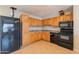 Well-lit kitchen featuring wood cabinetry and a full suite of black appliances at 1811 W Roma Ave, Phoenix, AZ 85015