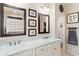 Bright bathroom featuring double sinks, marble countertops, framed mirrors, and decorative wall art at 1819 W Deer Creek Rd, Phoenix, AZ 85045
