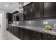 Modern kitchen featuring black cabinetry, stainless steel hood, granite countertops, and mosaic backsplash at 2219 E Galileo Dr, Gilbert, AZ 85298