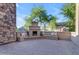 Serene outdoor patio featuring a stone fireplace, built-in seating, and lush greenery in the backyard at 2219 E Galileo Dr, Gilbert, AZ 85298