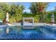 Gorgeous blue tiled pool with beautiful water feature wall in backyard, with lush greenery at 2219 E Galileo Dr, Gilbert, AZ 85298