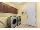 Functional laundry room with matching washer and dryer, upper cabinets, and tiled flooring at 2993 E Meadowview Dr, Gilbert, AZ 85298