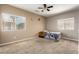 Neutral bedroom featuring two windows, a ceiling fan and clocks hung on the wall at 30165 W Flower St, Buckeye, AZ 85396