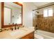 Bathroom with wood-trimmed mirror and vanity, decorative tiled shower, and updated fixtures at 4062 W Eva St, Phoenix, AZ 85051