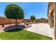 Spacious backyard with a custom fire pit, mature trees and manicured landscaping at 42519 W Centennial Ct, Maricopa, AZ 85138