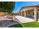 Beautiful backyard featuring a covered patio, fire pit, and mature landscaping at 42519 W Centennial Ct, Maricopa, AZ 85138