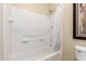 This bright bathroom has a white tiled shower and tub with shower rod at 42519 W Centennial Ct, Maricopa, AZ 85138