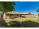 Landscaped backyard featuring lush green lawn, shade tree, block wall and cozy patio space at 5401 W Jessica Ln, Laveen, AZ 85339