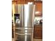 Close up of stainless steel refrigerator with wood cabinets, and stone countertops at 5616 W Hidalgo Ave, Laveen, AZ 85339