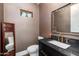 Powder room with dark fixtures, warm wall color, a decorative mirror, and floral accents at 6512 N 31St Way, Phoenix, AZ 85016