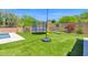 Landscaped backyard featuring artificial grass, trampoline, swing, and a sparkling pool for outdoor enjoyment at 7260 E Tasman St, Mesa, AZ 85207
